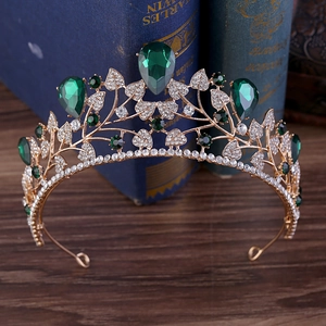 Golden baroque bridal crown with emeralds and rhinestones on a vintage book background