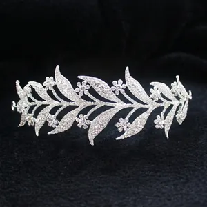 Detail view of bridal alloy crown with white rhinestones and leaf motifs on black velvet