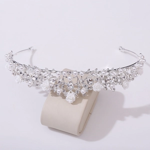 Dettaglio di tiara da sposa con strass argentati, perle e piccole rose bianche