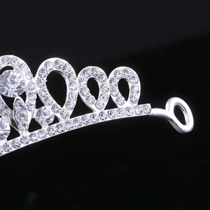 Macro detail of silver bridal tiara featuring intricate heart patterns and sparkling rhinestones