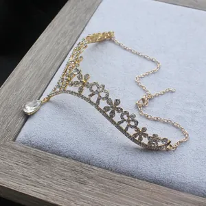 Macro detail of gold flower tiara with sparkling crystals and water drop pendant piece