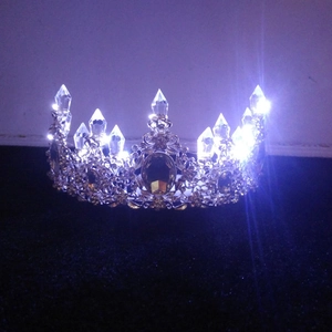 Detailed view of gold crystal crown showing bright LED lighting effects on dark background