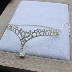 Close-up of silver bridal crown tiara with floral pattern and pear-cut crystal pendant