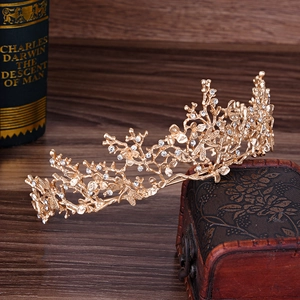 Elegante corona da sposa dorata con rami e cristalli scintillanti su scatola vintage