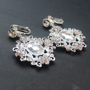 Macro shot of silver bridal earrings featuring oval crystals and intricate floral details