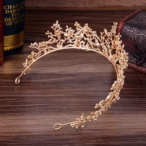 Corona a ramo dorata vintage con strass bianchi su superficie in legno scuro