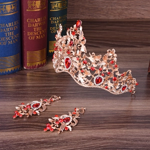Barokke gouden kroon en oorbellen set met rode strass steentjes op vintage houten achtergrond