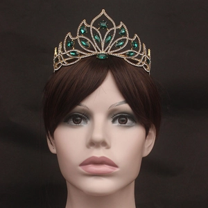 Detail view of gold bridal crown with emerald green gems and sparkling rhinestones
