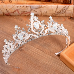 Elegant bridal crown with silver crystals, opals, and pearls on a vintage wood background