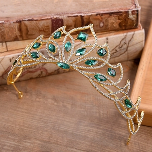 Detailed close-up of a gold bridal tiara with emerald green stones and white rhinestones