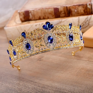 Macro detail of Baroque bridal crown with blue crystals and gold leaf filigree on wood