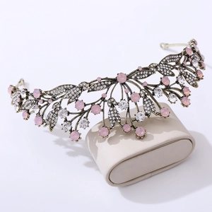 Close-up of vintage bridal leaf tiara with pink rhinestones and antique gold finish
