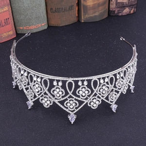 Macro view of luxurious silver crown with zircon drop pendants and vintage book background