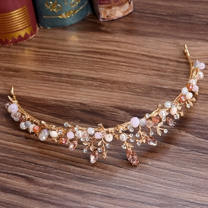 Handmade golden branch bridal crown with pink crystals and pearls on dark wood surface