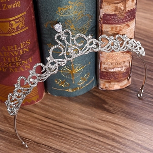 Elegant silver bridal crown with heart patterns and rhinestones on vintage books