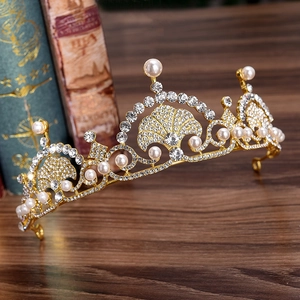 Luxurious gold bridal tiara with pearls and rhinestones on vintage wooden background