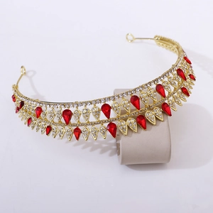 Macro detail of golden baroque bridal tiara with red teardrop rhinestones and crystals