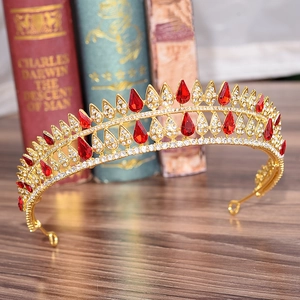 Detail view of gold baroque crown with red teardrop crystals on vintage book