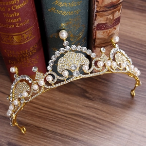 Elegant gold bridal tiara with pearls and rhinestones on vintage book background