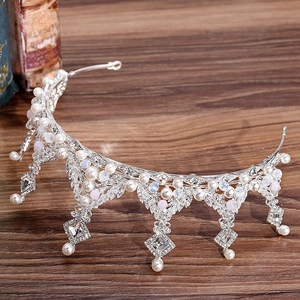 Exquisite silver bridal crown with white pearls, rhinestones and pink beads on wood background