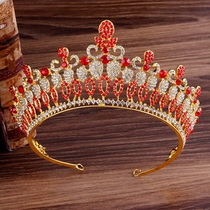 Detailed close-up of a gold Baroque crown with red rhinestones on a vintage wooden desk
