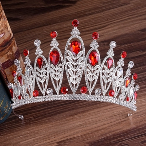 Baroque silver crown with red pear-cut rhinestones on vintage wood background