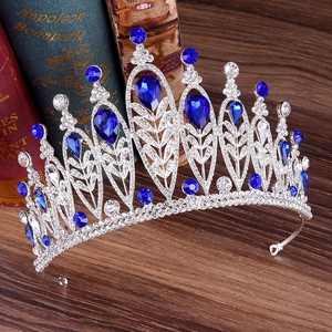 Close-up of silver baroque crown with deep blue crystals and rhinestones on wood