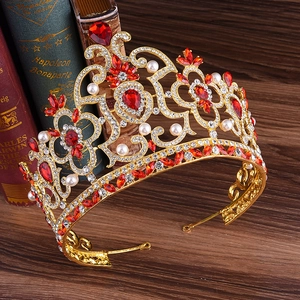 Gros plan d'une couronne baroque dorée avec cristaux rouges et perles sur livres anciens