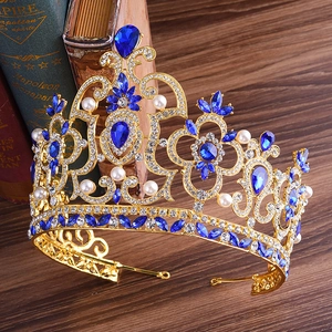 Détail d'une couronne baroque dorée avec gemmes bleues en goutte et strass blancs
