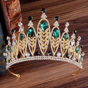 Macro detail of golden baroque crown featuring emerald green stones and diamond accents