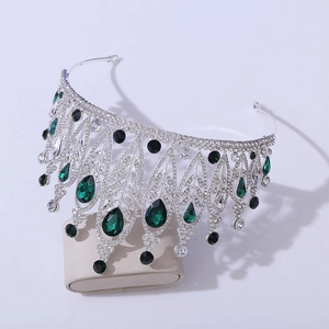 Detailed macro of silver tiara featuring leaf shapes and green emerald gemstones