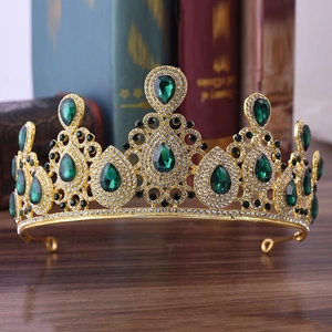 Detailed macro shot of vintage gold crown with green teardrop gems and small crystals