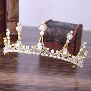 Close-up of golden bridal crown with white pearls and sparkling crystals on wooden table