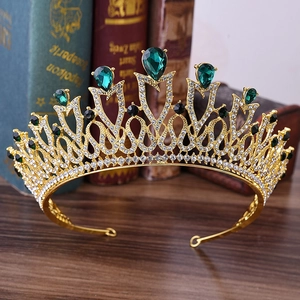 Macro detail of golden bridal crown with emerald teardrop stones and white crystals