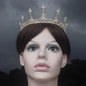 Close-up of golden bridal tiara with sparkling white rhinestones and pearls on a model