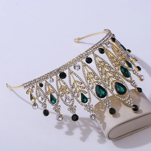Detailed side view of baroque crown with green teardrop gems and white rhinestones
