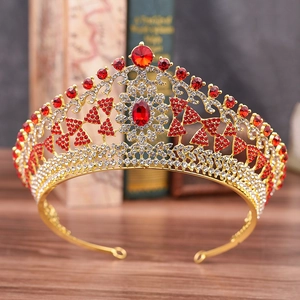 Close-up of golden bridal tiara with red crystals on vintage books and wood
