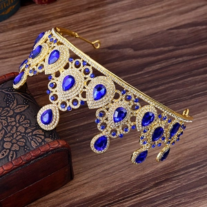 Close-up of golden bridal tiara with blue teardrop gems and rhinestones on a wooden box