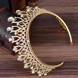 Detailed close-up of golden bridal crown with white rhinestones on dark wood background