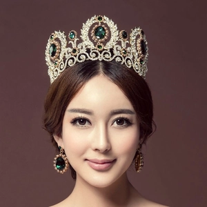 Detailed close-up of Baroque crown and emerald earrings with pearls and rhinestones