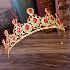Detailed view of a gold bridal crown with red teardrop rhinestones on dark wood