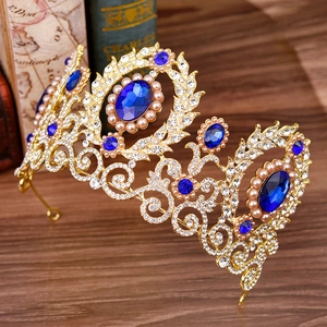 Close-up of golden baroque tiara with navy blue gemstones and white pearls on vintage book