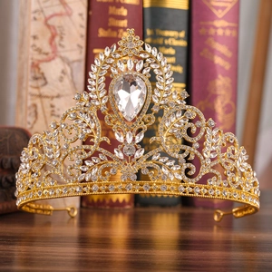 Luxuriöse goldene Barock-Brautkrone mit Kristallen auf Holztisch und Buchhintergrund