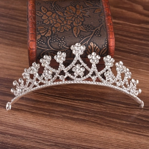 Elegant silver tiara with rhinestones and floral design on vintage wooden background