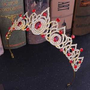 Détail d'une couronne dorée vintage avec pierres rouges et cristaux sur fond sombre