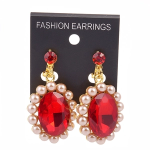 Detailed macro view of baroque gold earrings featuring red gemstones and pearls
