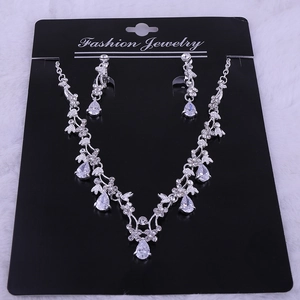 Detail of silver drop necklace and earrings set with zircons on black display card