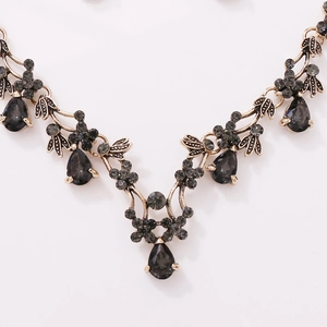 Vintage bronze necklace with drop-shaped gray crystals and floral details on white backdrop