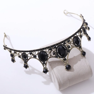 Close-up of vintage bronze crown with black crystals and oval gems on jewelry stand