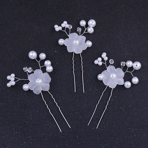 Close-up of handmade bridal hair pins with frosted flowers, pearls, and crystals